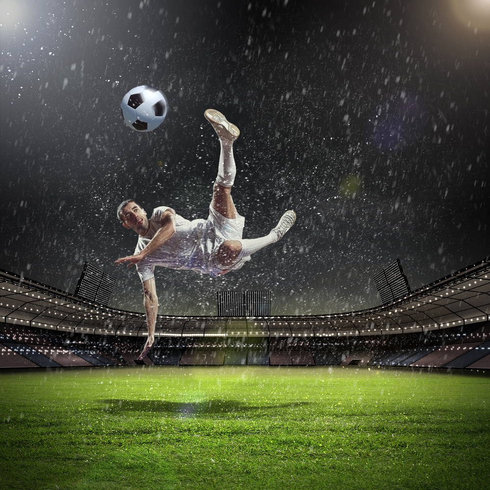 Soccer player kicking soccer ball while perpendicular to the ground.